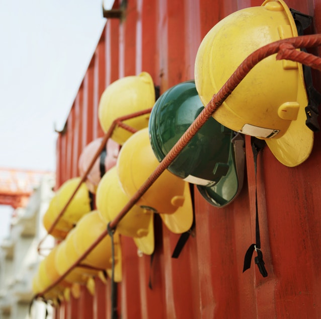 Yellow and red safety helmets, hung up on the side of a red shipping container.