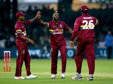 Three Windies cricket team players celebrating a victory in the field.