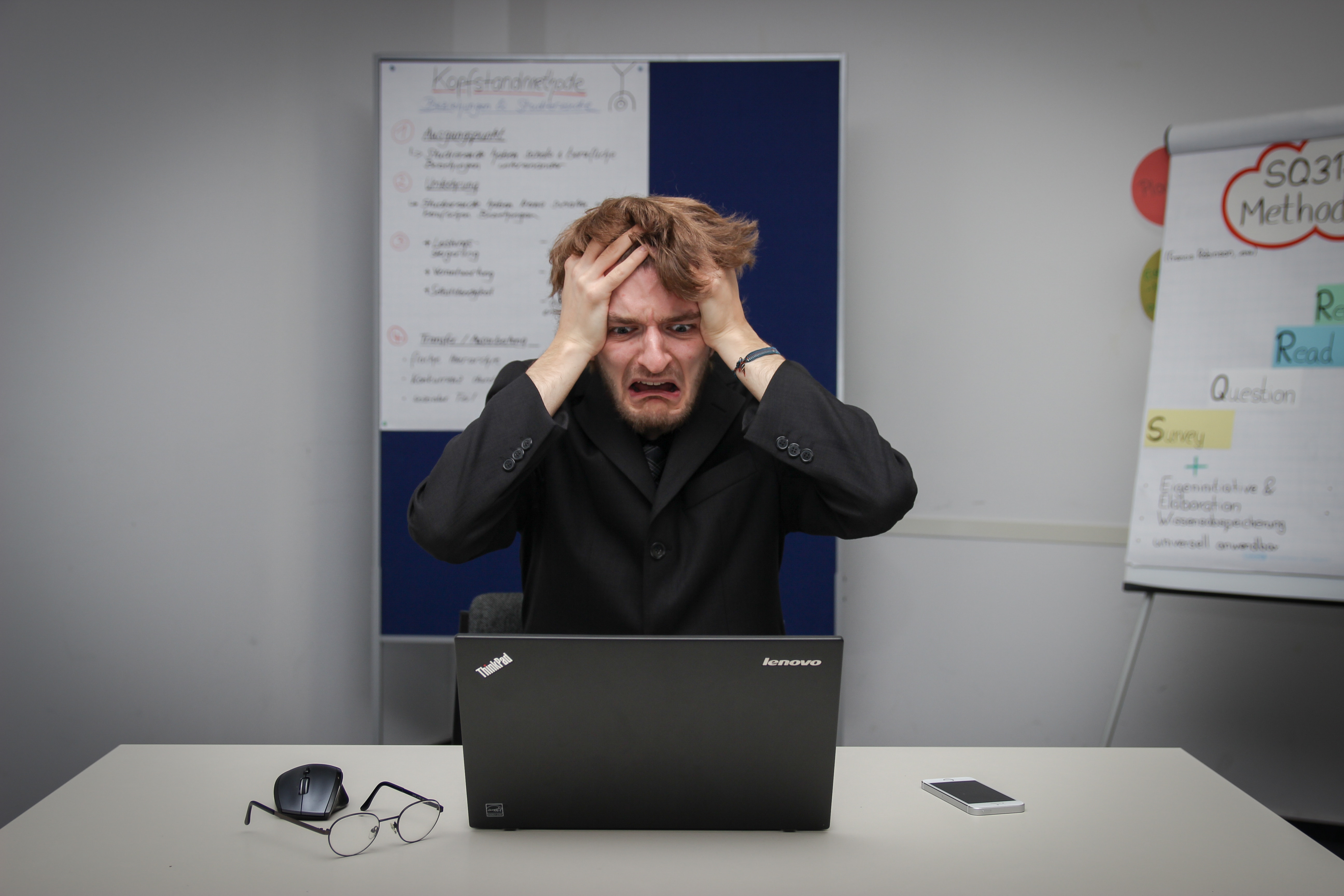 Worried man sitting at his desk looking at an open laptop