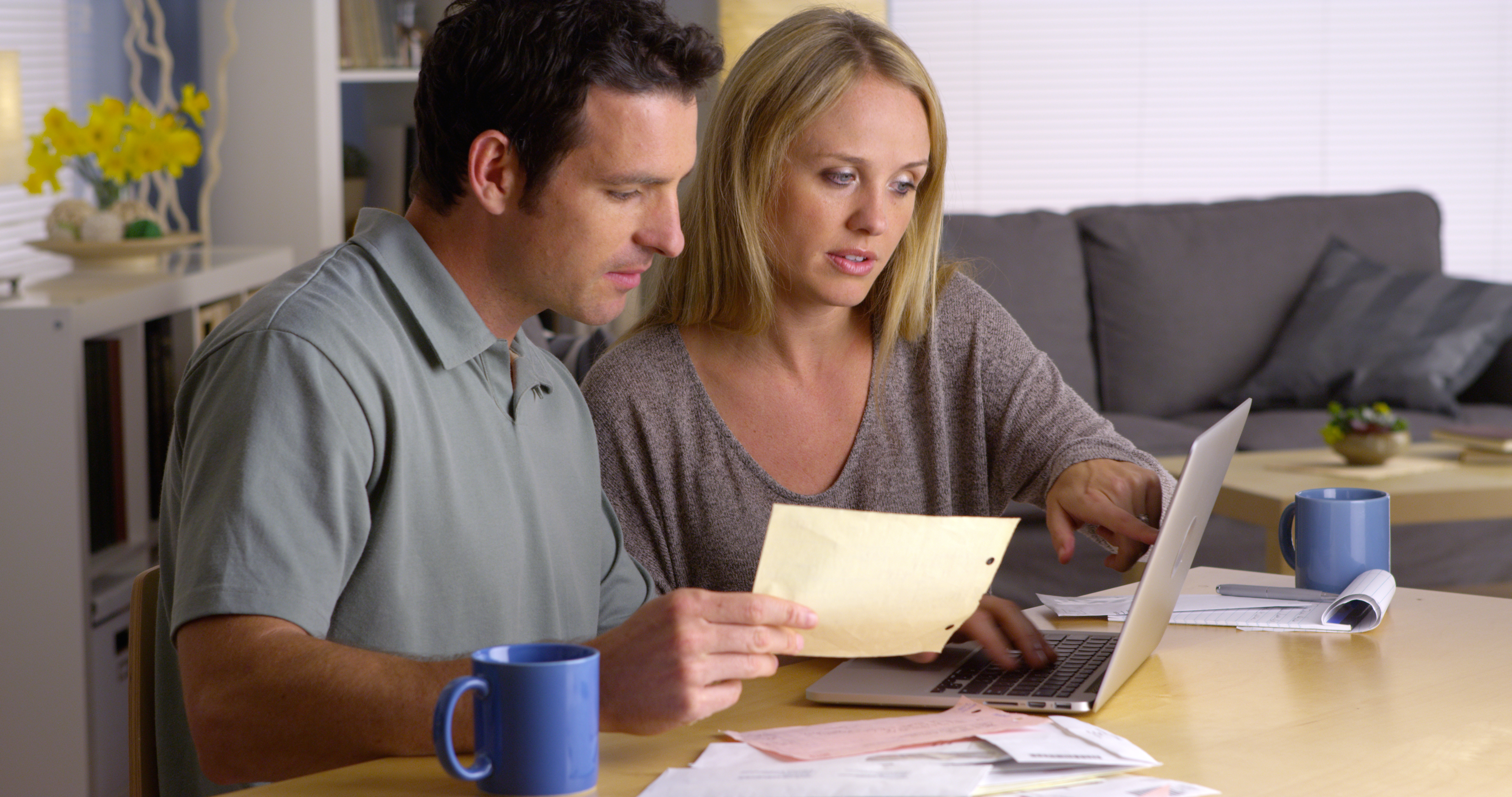 Couple at computer studying paperwork together.