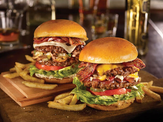 Two triple-decker bacon and cheese burgers with chips.