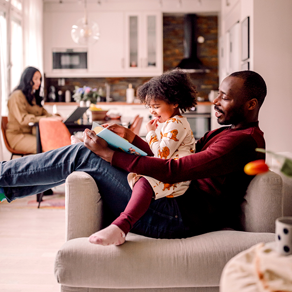 Dad reading to daughter while they sit on the couch