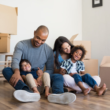 Family of 4 sitting on the floor in their home with boxes in the background | Knowing what you can afford | Hippo partner