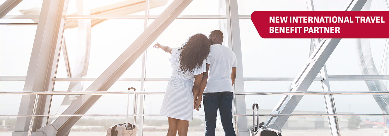 Couple with suitcase looking out airport window