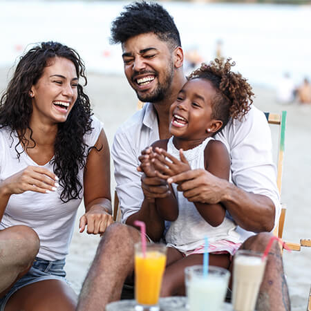 Family of 3 laughing on the beach
