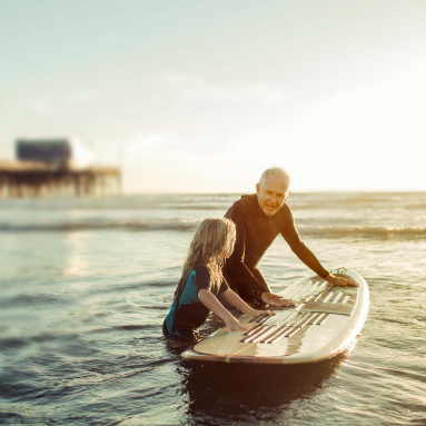 Grandfather teaching child to surf | History of our brand | Hippo.co.za partner