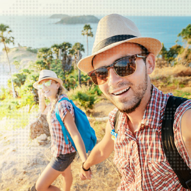 Couple walking hand in hand down a mountain with the ocean in the background as they take a selfie | About Hepstar travel insurance | Hippo.co.za partner