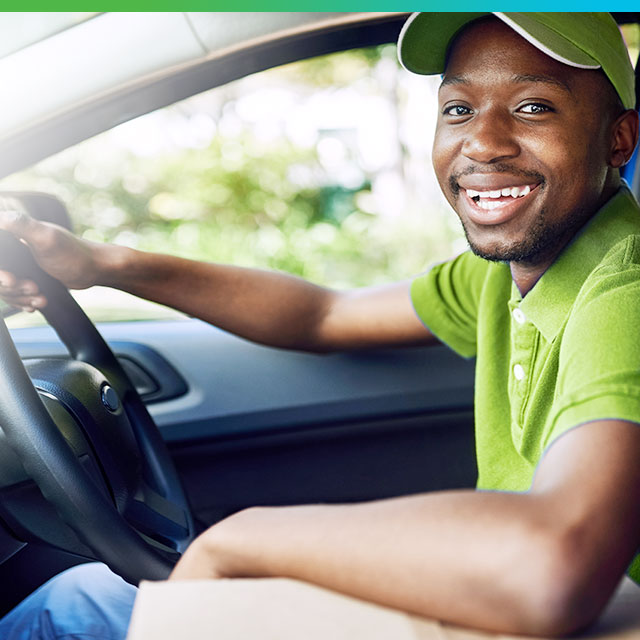 Guy smiling as he drives vehicle and looks at camera | Car insurance that goes the extra mile | Hippo.co.za partner
