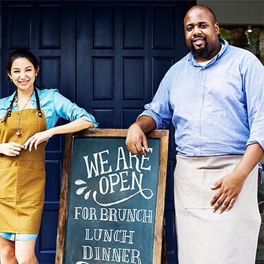 Chef and manager standing outside welcoming patrons in for lunch and dinner