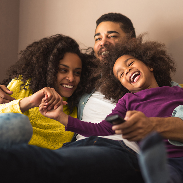 Family of 3 on the couch laughing