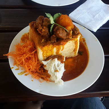 Bunny Chow, a hollowed-out half loaf of bread filled with meat curry served with carrots.