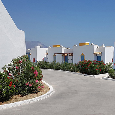 Entrance with flowers and trees on the sides at Koos Hotel, Greece.