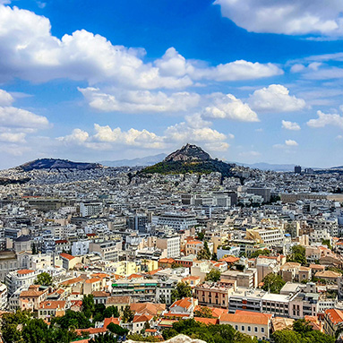 Aerial view of Athens, with a cloudy sky in the background.