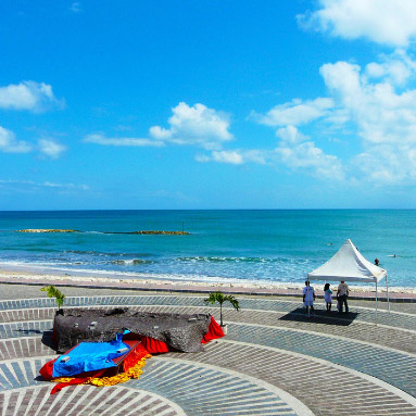 People standing under the gazibo with the sea and cloudy sky in the background