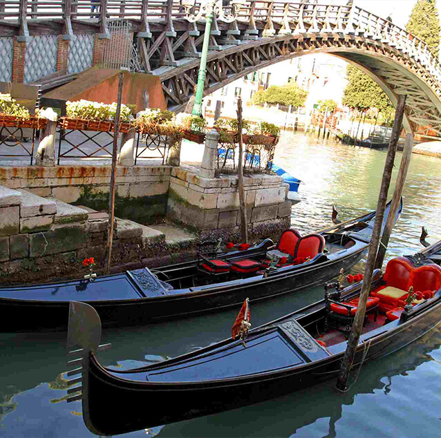Two gondola rides on water with a small bridge in the background.