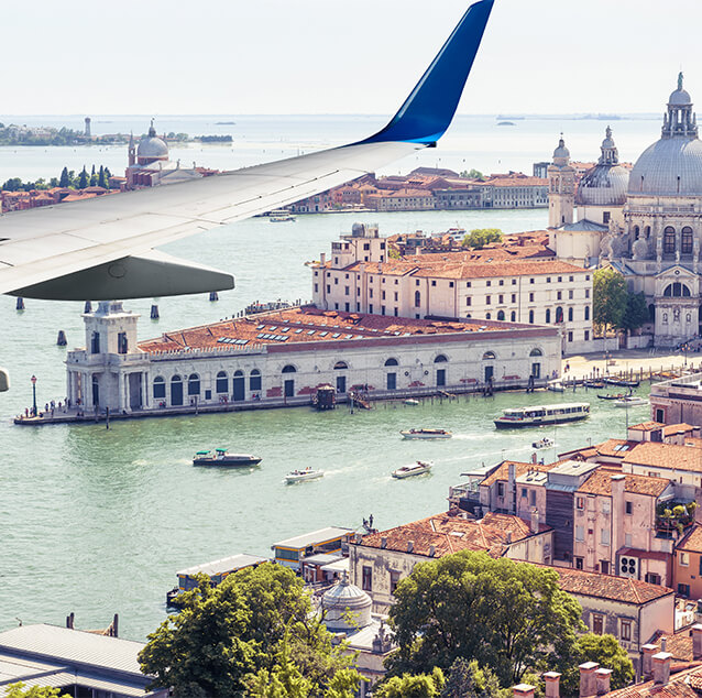 Airplane wing view with view of Italy in the background.