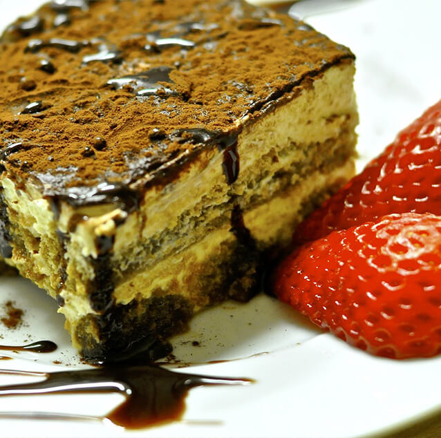 Tiramisu cake with strawberries on a white plate.