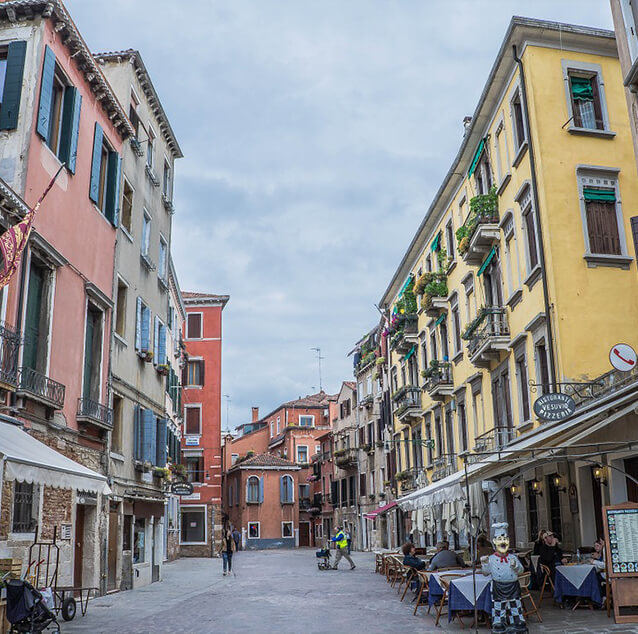 A street with restaurants and shops on both sides in Venice, Italy.