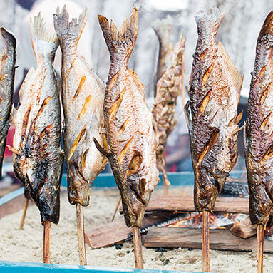 Open-fire cooked fish on sticks ready for eating