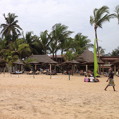 Gazebos on the beach with palm trees in the background.