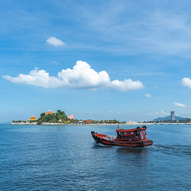 Small red boat on the sea travelling close to land