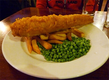 A plate of traditional English fare: fish and chips with peas.