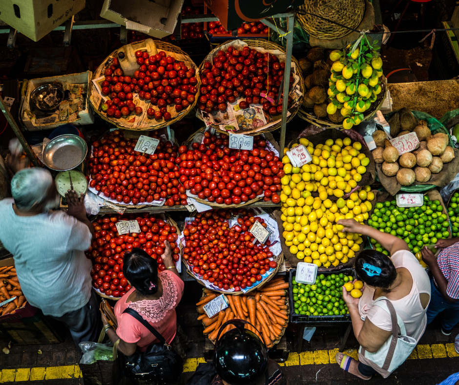 Man pushing bicycle on the beach with the sea and cloudy sky in the background.