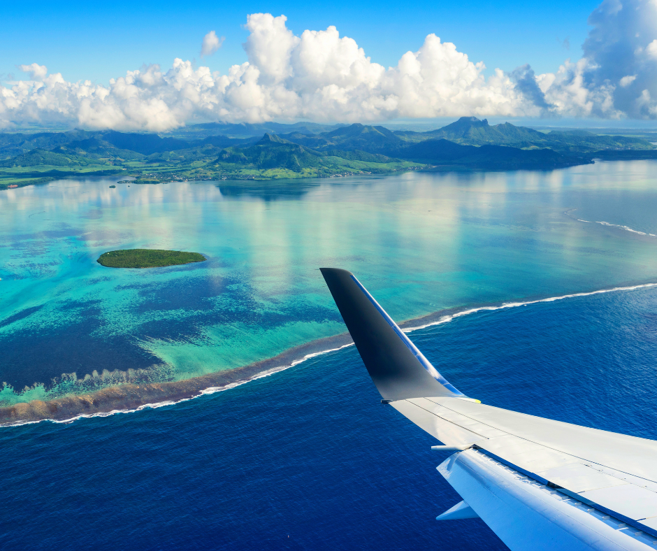 People on a boat in the sea with trees and blue cloudy sky in the background.