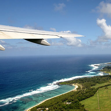 Airplane wing with sea and cloudy sky in the background.