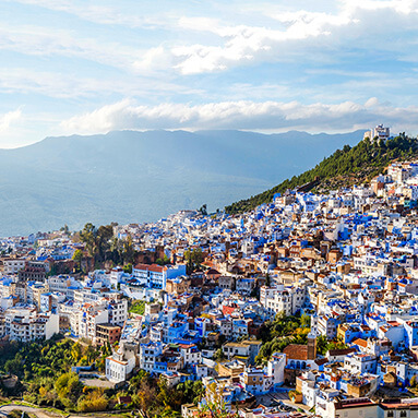 Beautiful green Moroccan valley with blue and white houses and blue sky in horizon.
