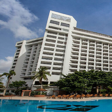 Large white modern hotel with pool in front