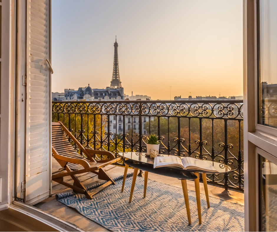 Man and woman wearing white rooms and carrying mugs standing at the balcony.