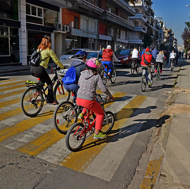 People cycling on the street with buildings in the background.
