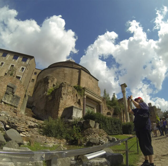 Taking a picture with people and antient buildings in the background.