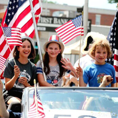 People sitting in the car carrying American flags