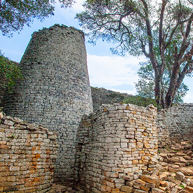 Ancient ruins of great Zimbabwe with green tree and dilapidated stone wall.