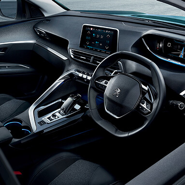 Black interior of peugeot with steering wheel, seats and gear.