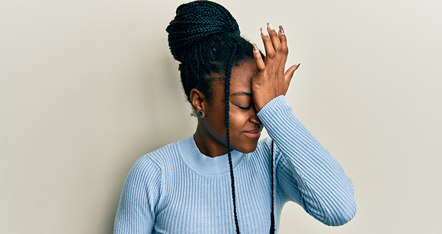 A young woman holding her hand to her forehead 