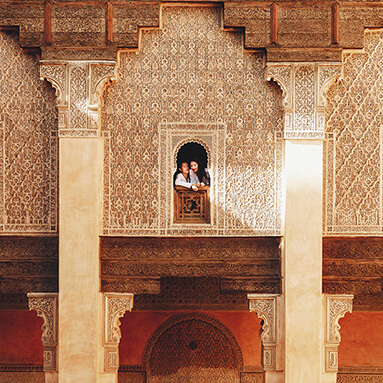 Two women looking outside of building with Egyptian patterns decorated on walls.
