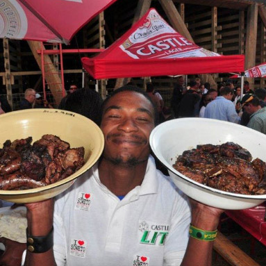 Waiter holding up dishes of grilled beef and sausages