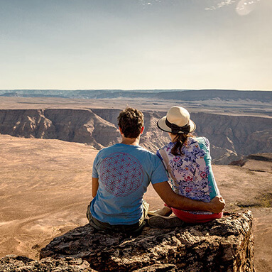 Romantic couple sitting on a cliff overlooking the Namib desert