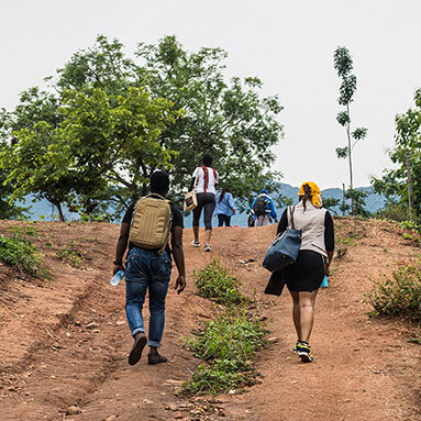 People walking on a steep slope with trees on top of the slope.