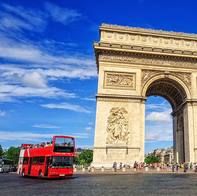 The Arc de Triomphe de l'Étoile monuments with a red tour bus and tourists.